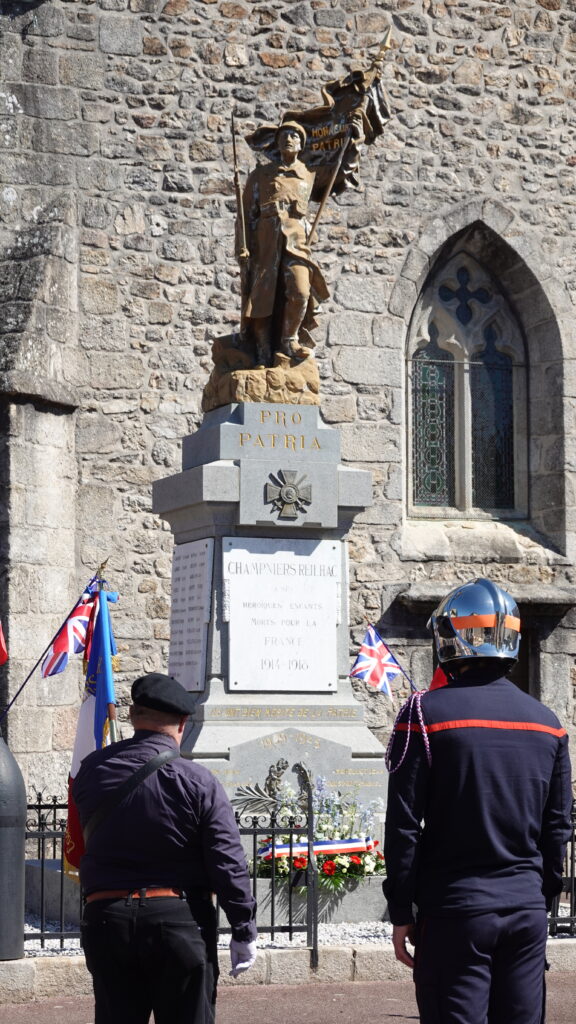 Photo du monument aux morts lors de la cérémonie du 8 mai 1945 avec un porteur de drapeau et un pompier